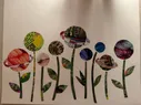 A collage of various patterns cut out in the shape of planets (some with rings, some without) on top of stems with leaves