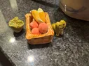 A collection of fired clay pieces, including a basket, carrots, apples, a cabbage, and a frog