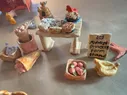 A ceramic farm stand with various baked goods, flowers, and fruit