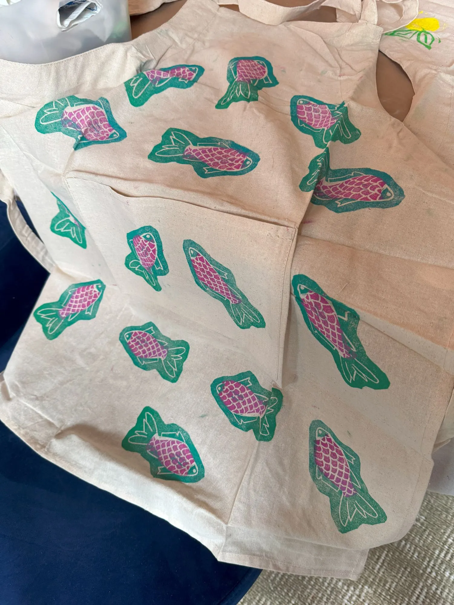 An apron with block-printed fish in turquoise and pink ink