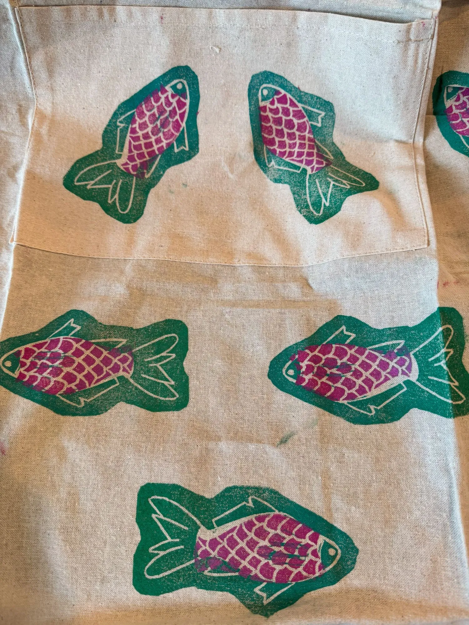 A closer look at an apron with block-printed fish in turquoise and pink ink