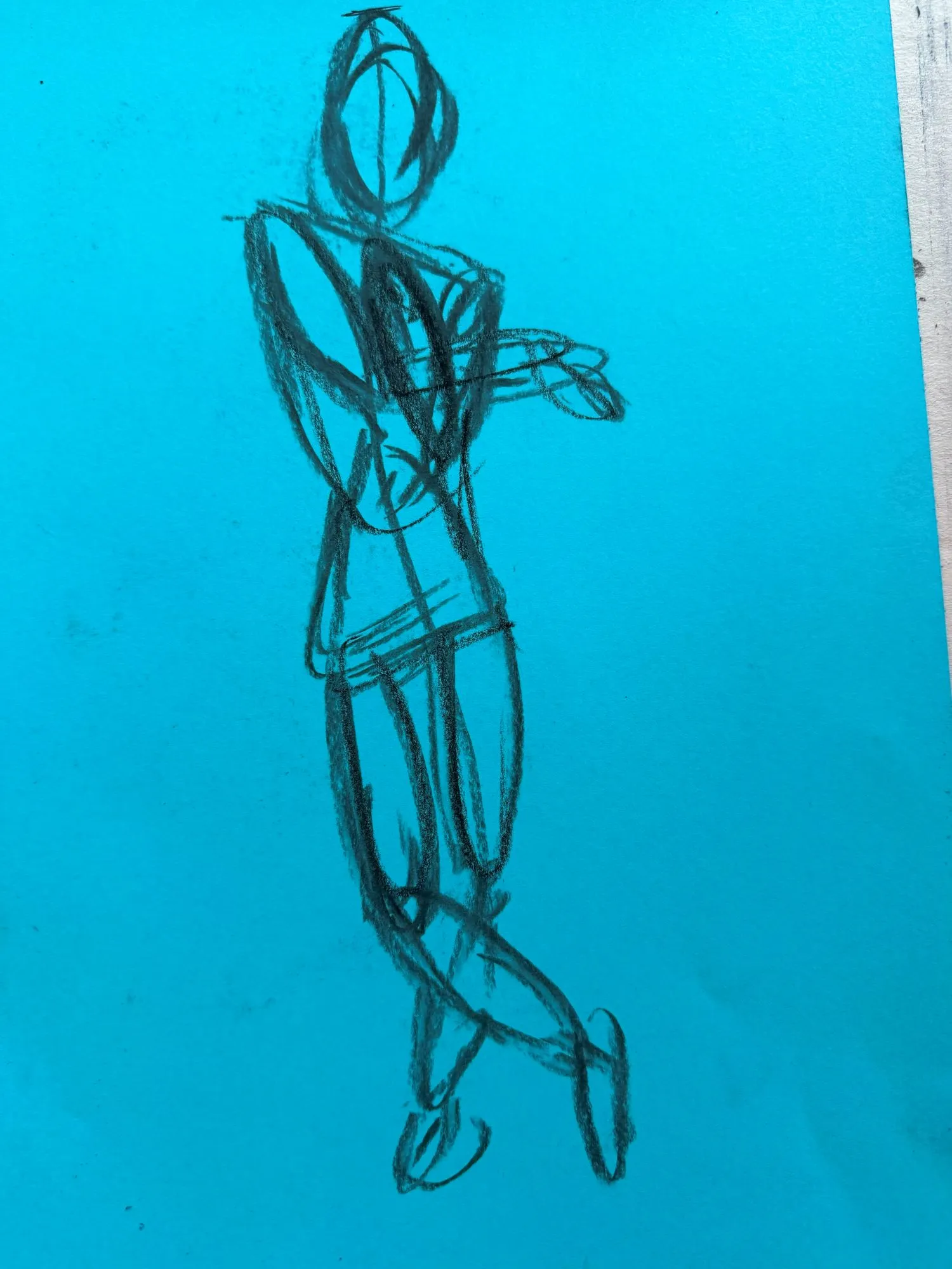 A quickly-drawn figure in charcoal on blue paper