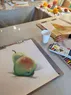 Drawings on a table with the fruit reference visible in the background