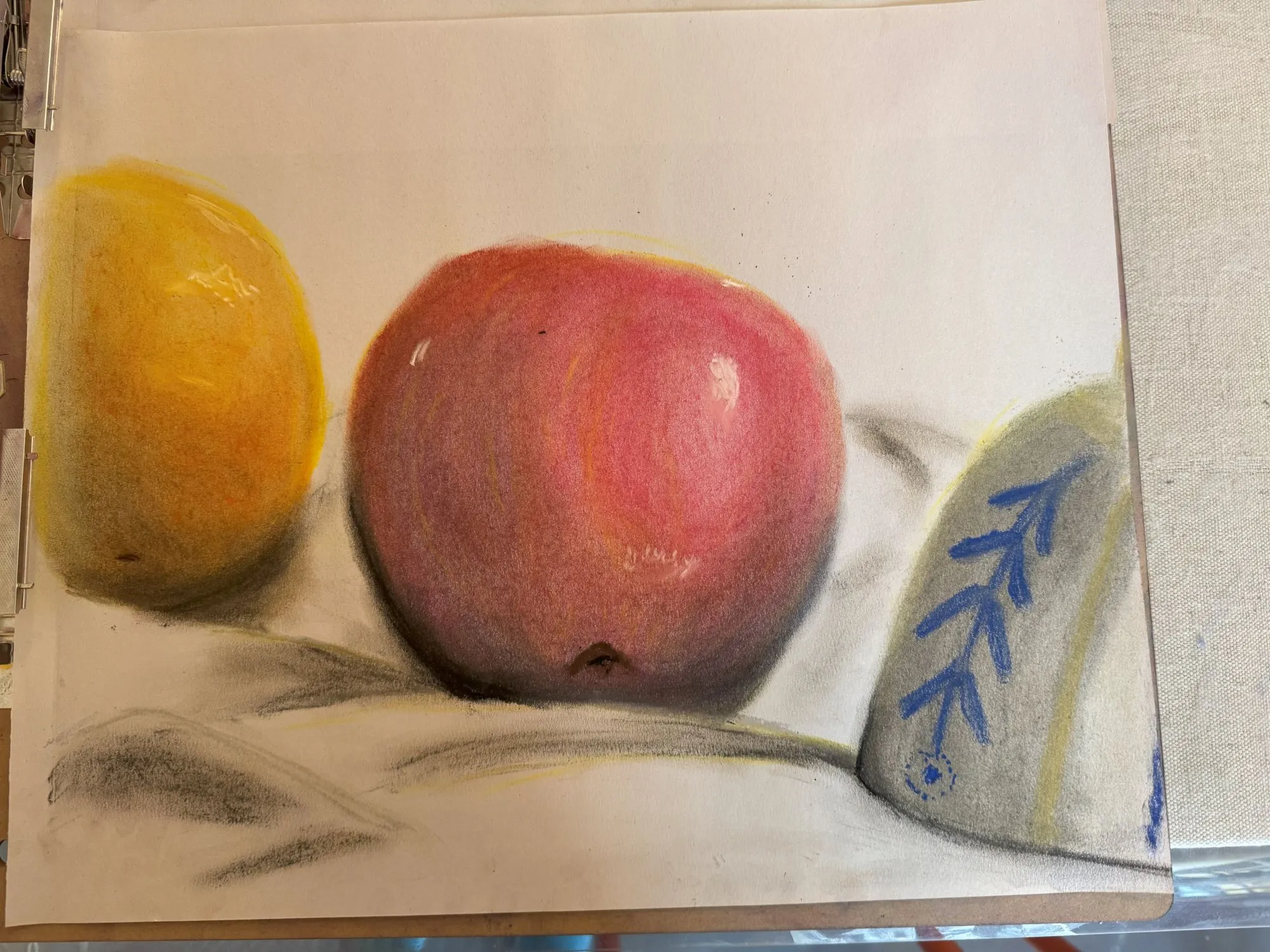 An apple with an orange and part of an overturned bowl on either side, drawn in chalk pastel