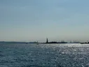 A picture of water with a silhouette of the Statue of Liberty visible in the distance