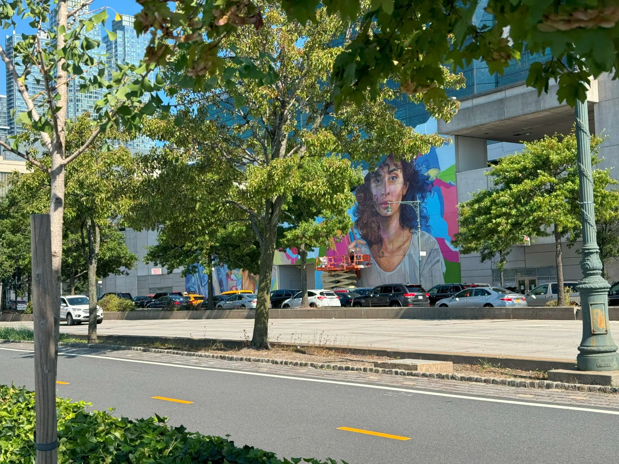 A painting of a woman on a wall across a busy street