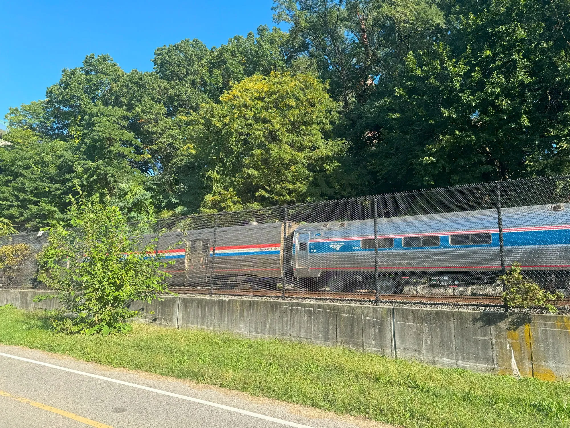 An Amtrak train going by behind a fence