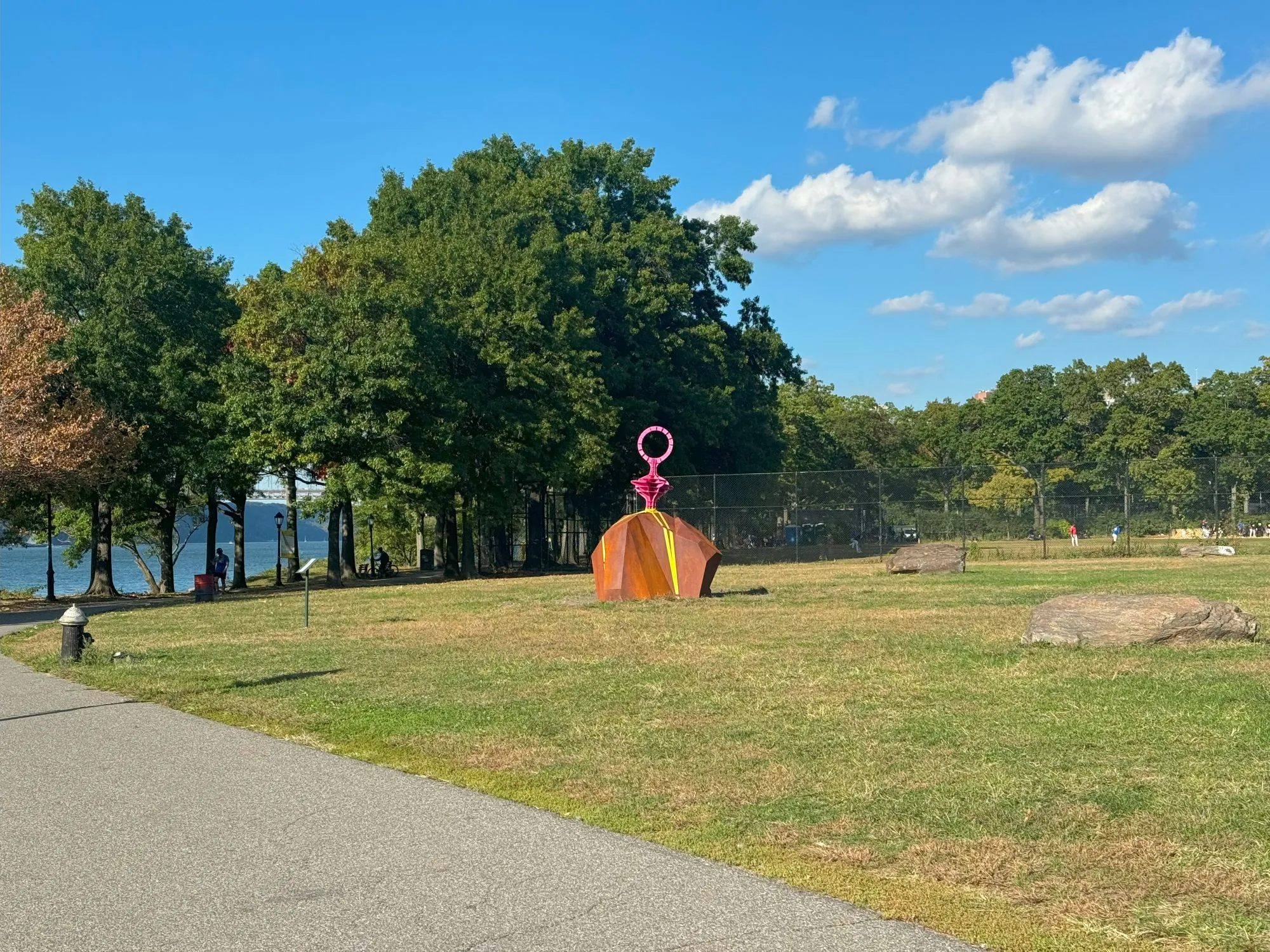A statue in a park that looks like a boulder with a pink structure sticking from the top