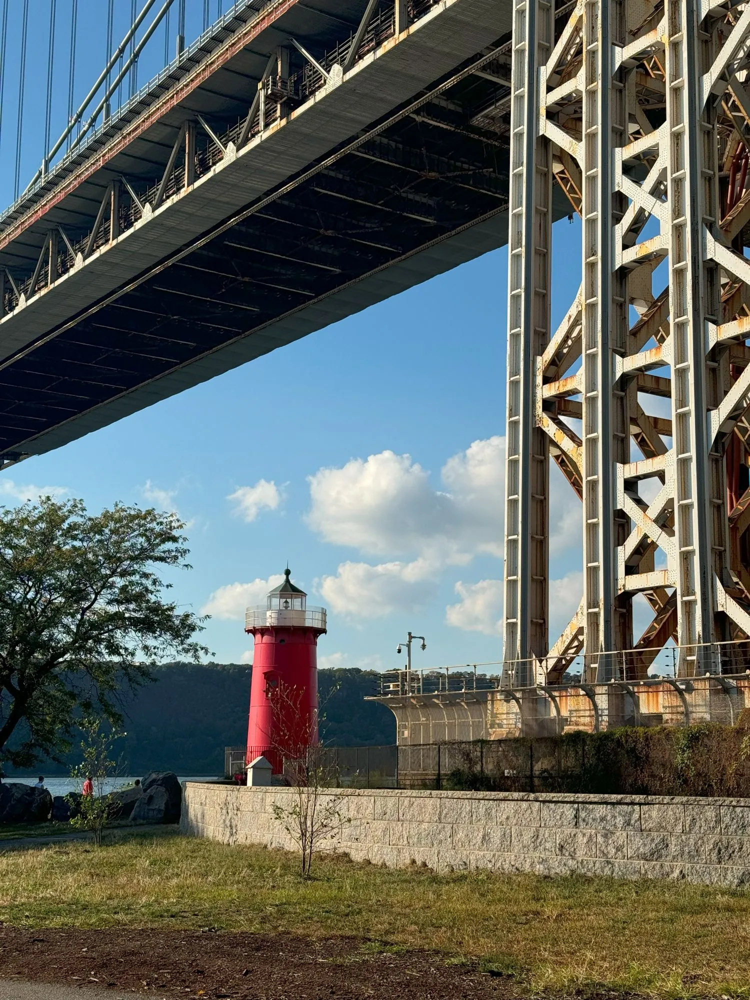 A small red lighthouse under a bridge