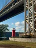 A small red lighthouse under a bridge