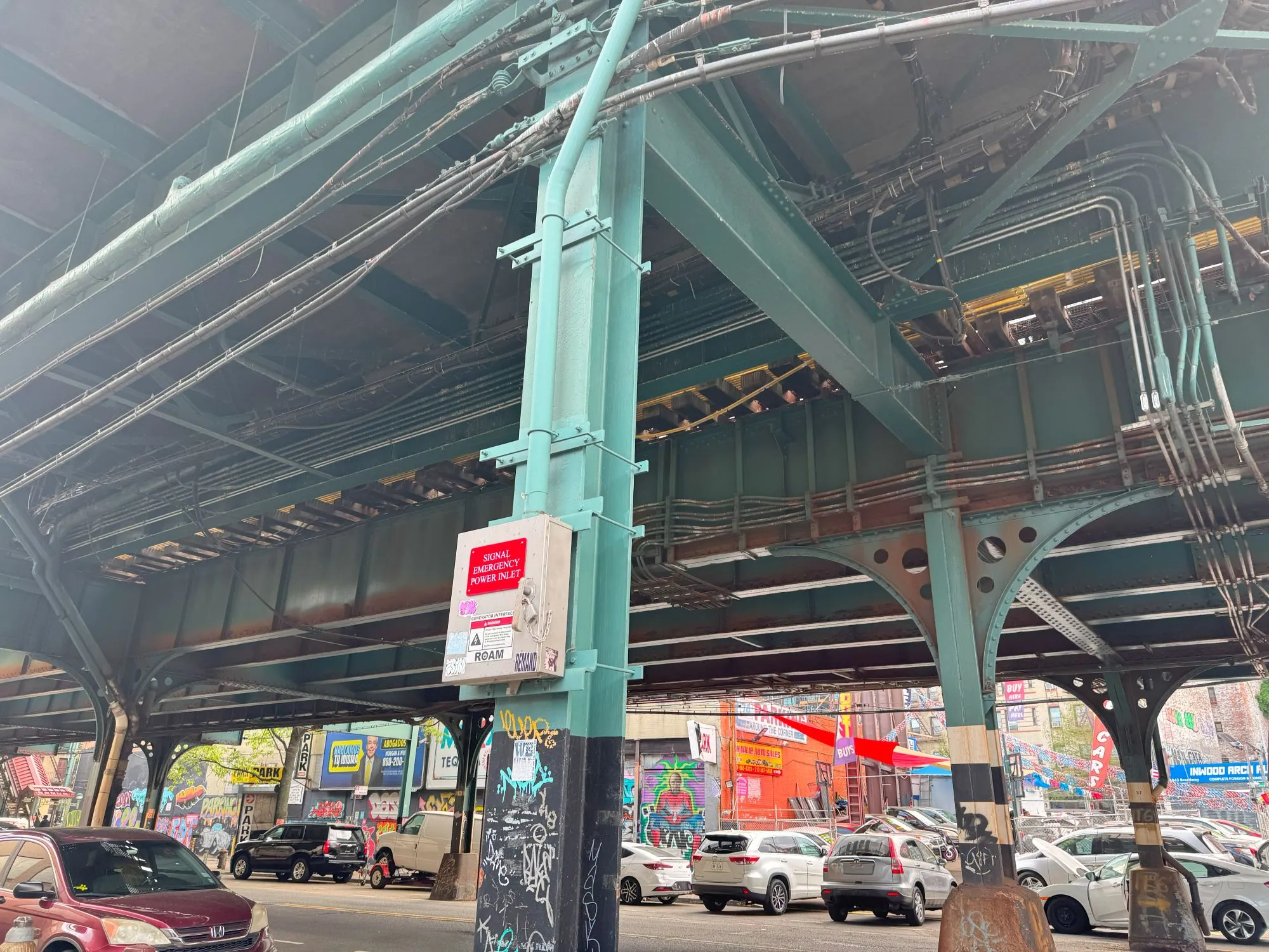The underside of a highway with cars parked under it