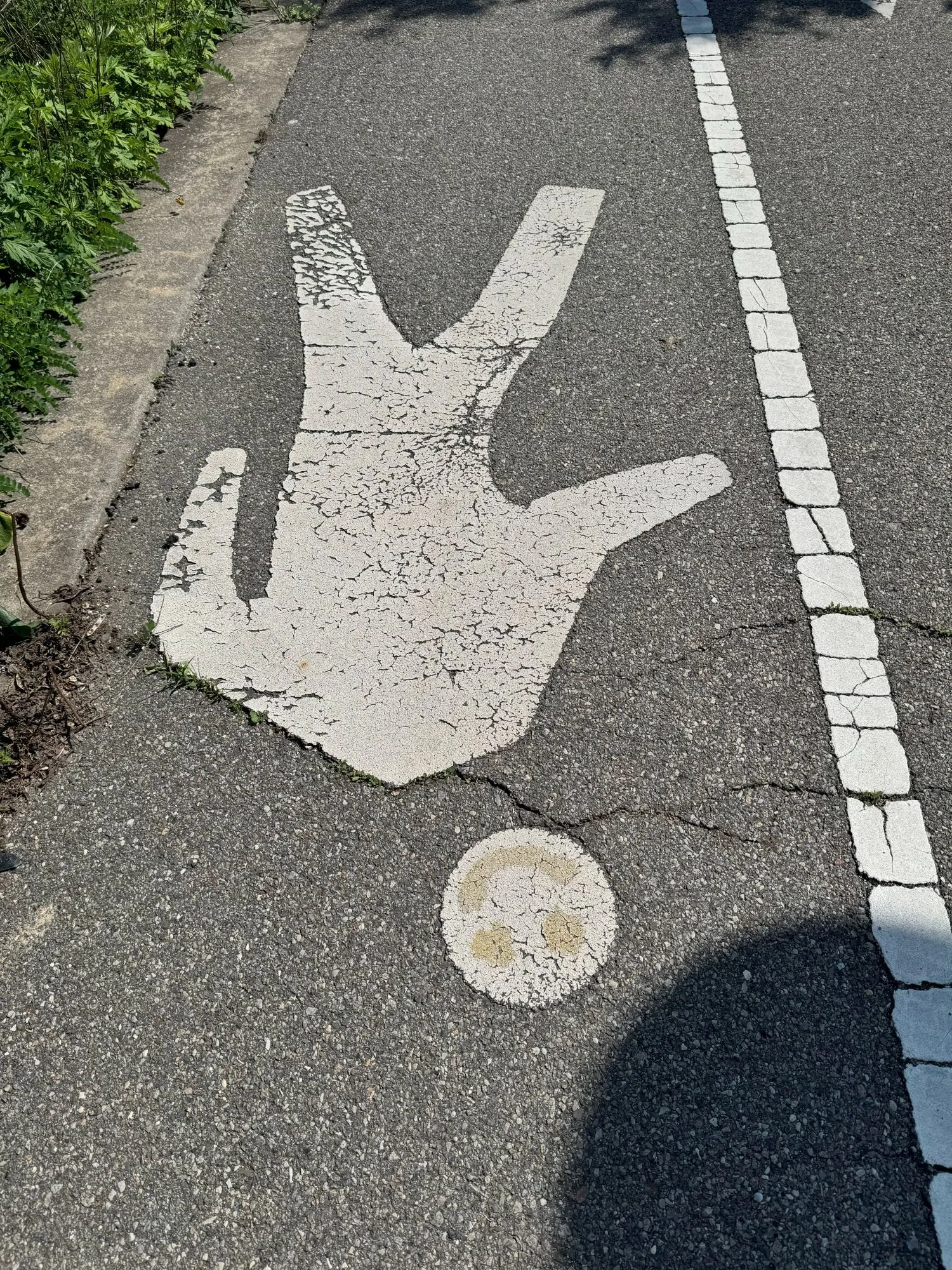 A pedestrian icon on a walking path, with a smiley face painted on the head