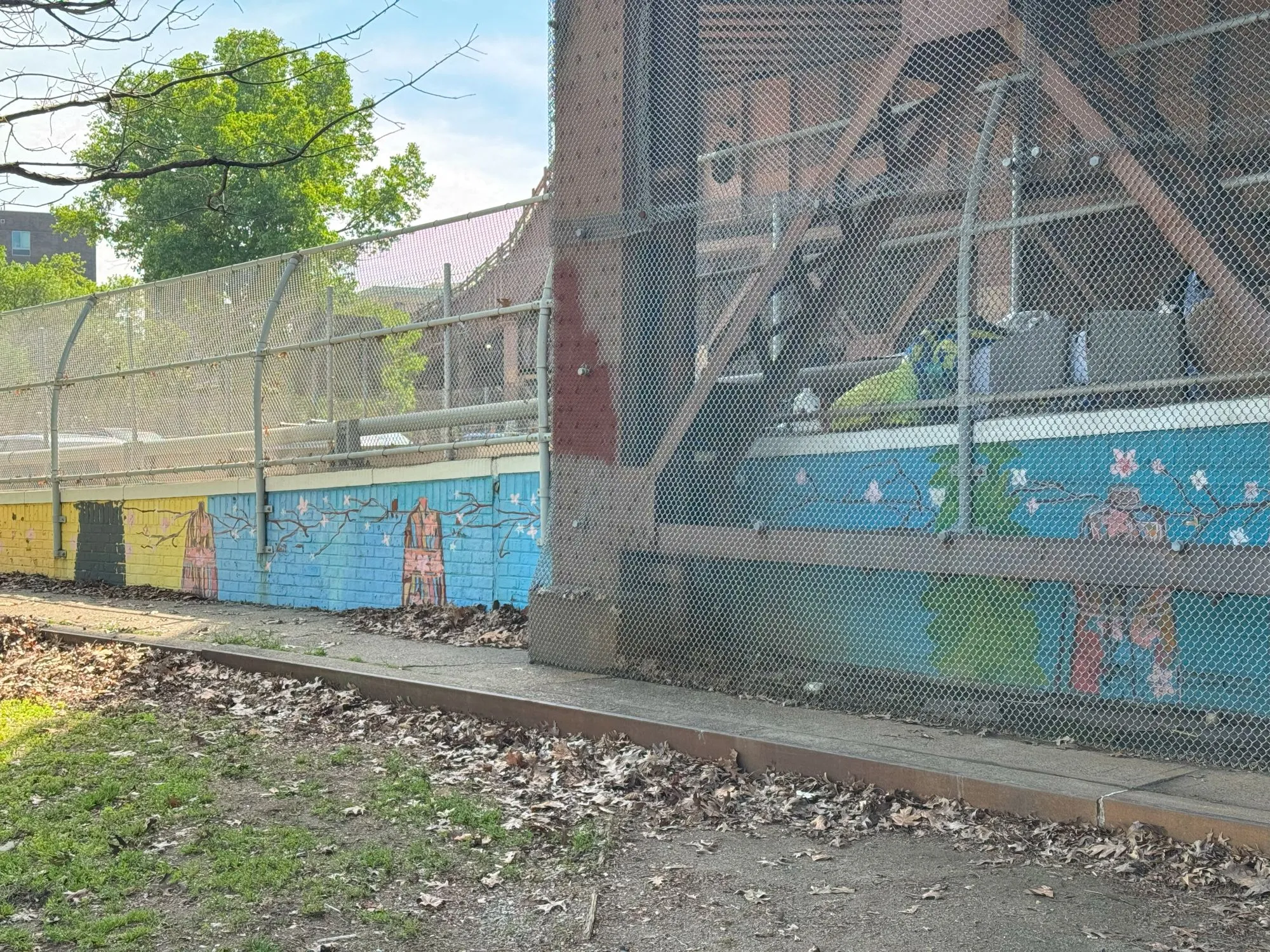 A mural showing branches with blossoms along a wall underneath a bridge