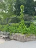 A fence covered in ivy with a bench beneath it