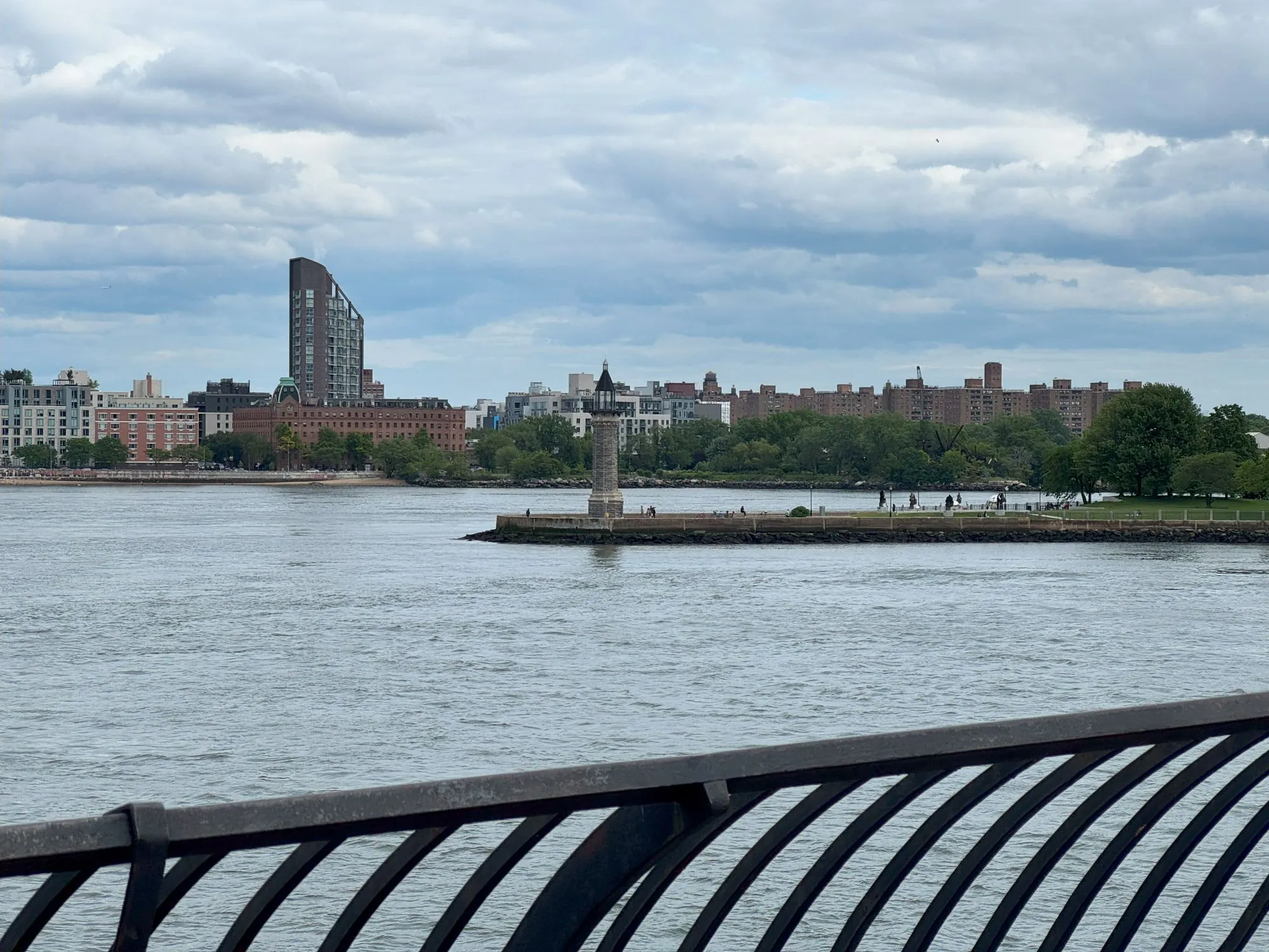 A small lighthouse on the end of an island in the middle of the river