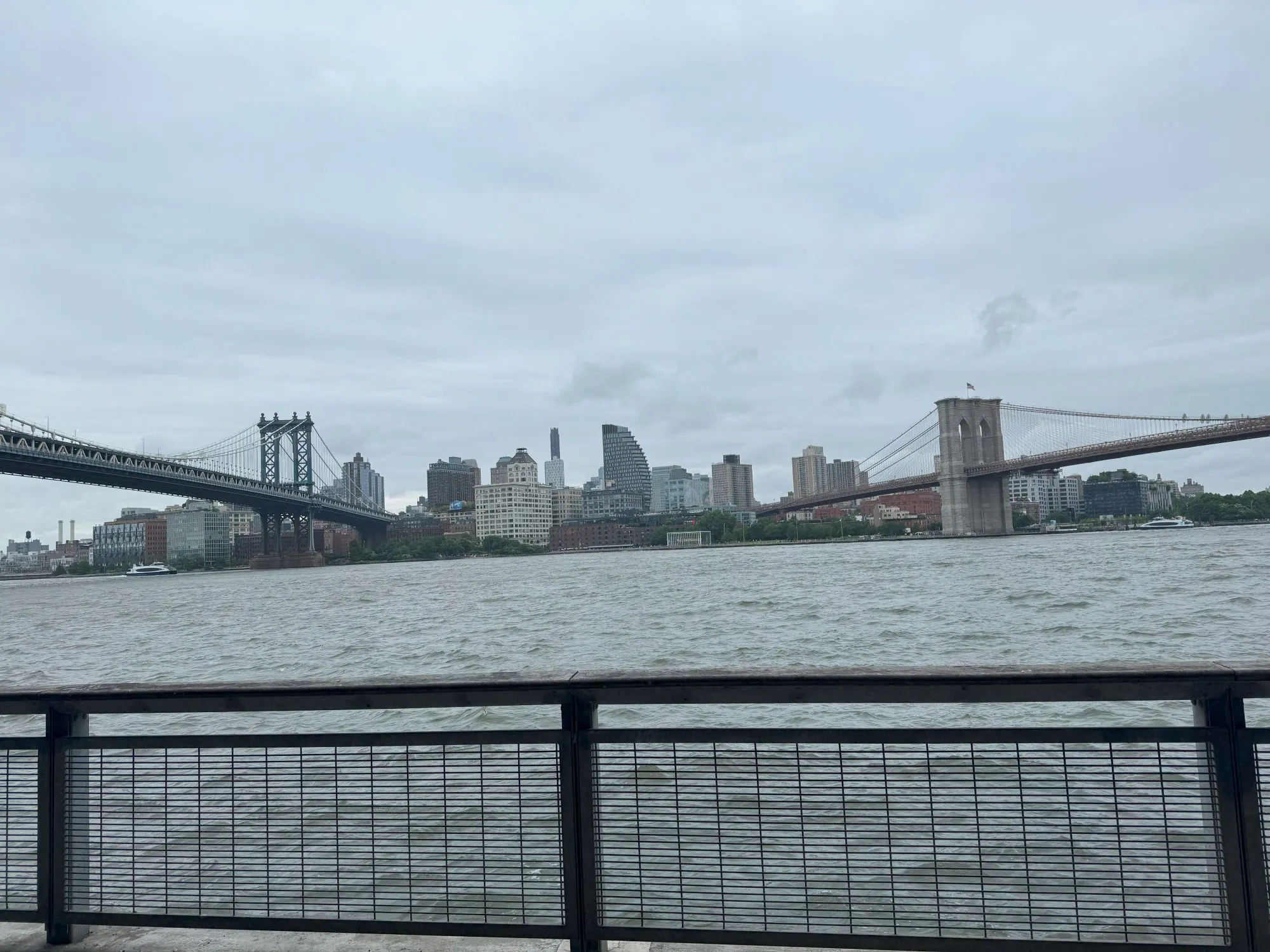 The Manhattan and Brooklyn Bridges visible on either side of the image, both going over the river