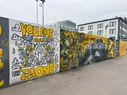 A series of murals in black, white, gray, and yellow, with the words 'You are not alone' on each