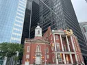 A small brick church surrounded on all sides by glass skyscrapers