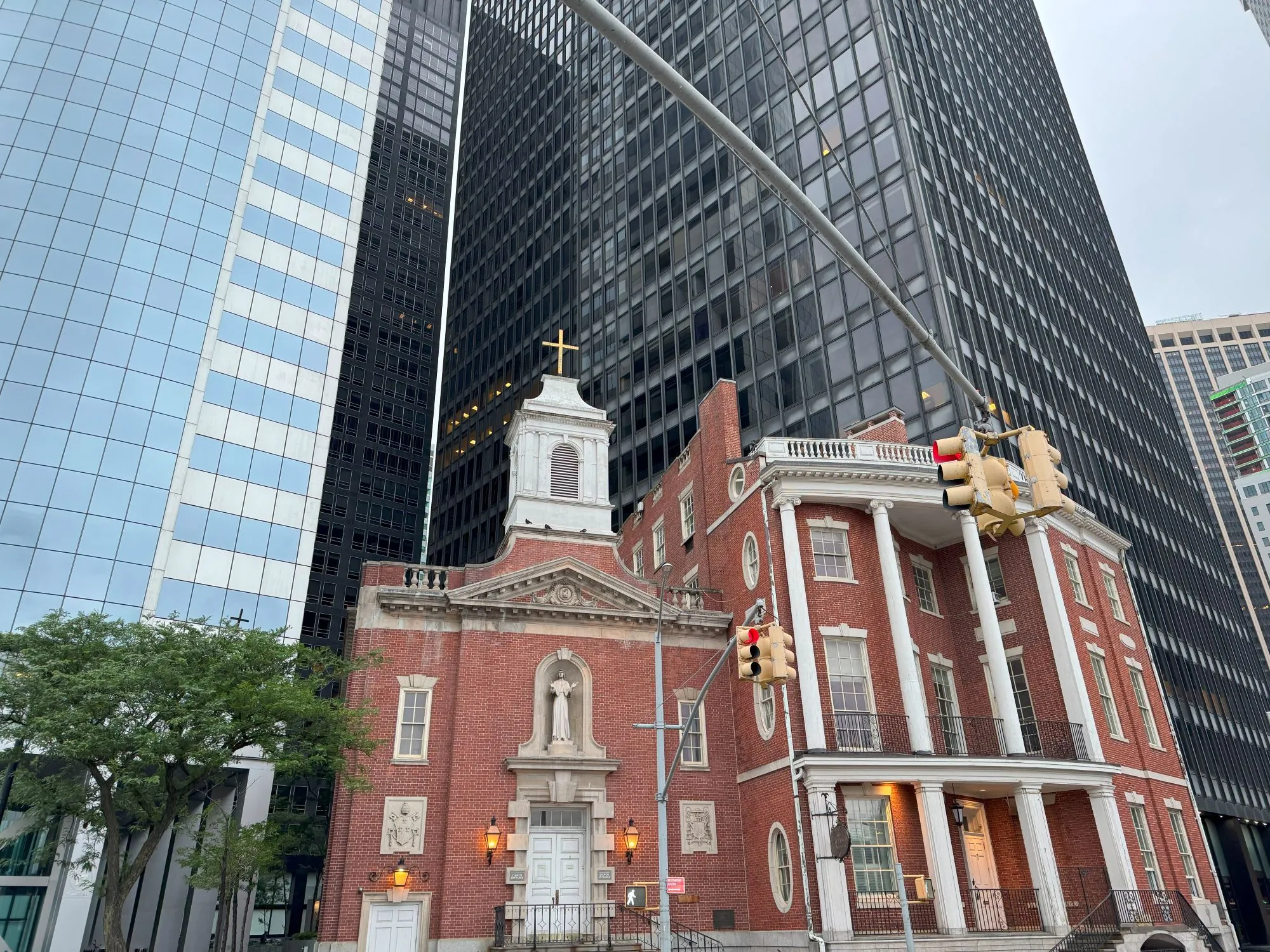 A small brick church surrounded on all sides by glass skyscrapers