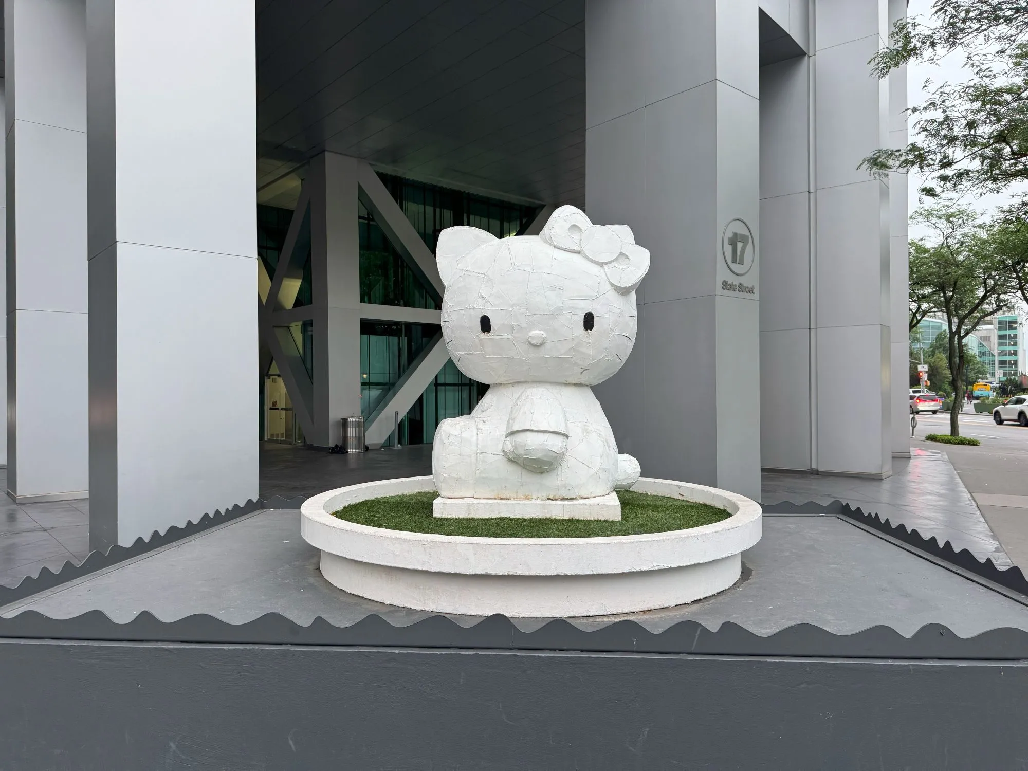 A statue of Hello Kitty in front of a modern skyscraper